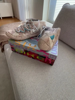 Nike Kyrie 5 Beige Camo Sneakers - Unika Nike Kyrie 5 sneakers med beige camo-mönster och turkosa detaljer. Skorna har en hög siluett, robust sula och cool design med flera lager och texturer. Perfekta för dig som gillar basketinspirerade sneakers och vill sticka ut med färg och mönster.