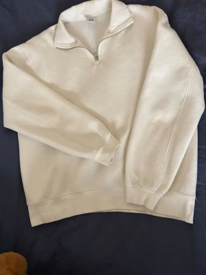 Vit halvzip hoodie från Zara - Säljer en beige hoodie från Zara med halvzip och hög krage. Tröjan är tillverkad i mjukt bomullsmaterial och har ribbade muddar vid ärmslut och nederkant. Perfekt för en chill och avslappnad look. Tveka inte på att ställa frågor!