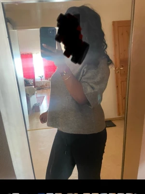 Grå stickad tröja med kort ärm - Mysig grå stickad tröja med breda, korta ärmar och rund halsringning. Tröjan har en avslappnad passform och är tillverkad i ett mjukt, fluffigt material som känns skönt mot huden. Perfekt att styla med jeans eller kjol för en chill look.