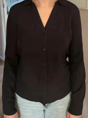 Skjorta - Svart v-ringad skjorta från H&M i mycket fint skick. Material: Polyester