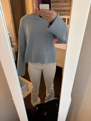 Ljusblå oversized stickad tröja - Mysig ljusblå stickad tröja med oversized passform och breda ärmar. Tröjan har ribbstickade muddar vid ärmslut och nederkant samt en rund halsringning. Perfekt för lager på lager och en avslappnad stil.