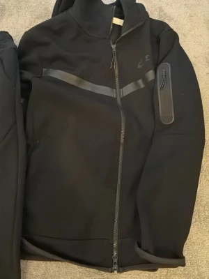 Svarta mjukisbyxor från Nike - Säljer ett par svarta mjukisbyxor från Nike med diskret logga på benet. Byxorna har resår i midjan med dragsko och är gjorda i ett mjukt och bekvämt material. Perfekta för chill eller träning. Passar 180-183