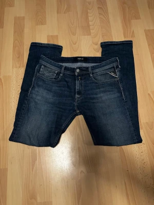Mörkblå jeans från Replay - Storlek  W30 L32. Säljer ett par snygga mörkblå jeans från Replay med klassisk femficksmodell och diskreta slitningar. Jeansen har raka ben och är tillverkade i mjukt denimtyg med snygga kontrastsömmar. Perfekta för en avslappnad och trendig look.
