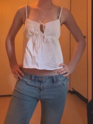 linnetopp - Säljer en vit linnetopp med smala axelband och snygg snörning framtill. Toppen är croppad och har en luftig passform som passar perfekt till jeans eller shorts. Aldrig använd men utan prislapp!💗
