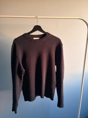 Mörkblå ribbad tröja - En stilren mörkblå tröja med ribbad struktur och rund hals. Tröjan har långa ärmar och är tillverkad i ett mjukt material som ger en skön känsla. Perfekt för dig som gillar minimalistisk design och vill ha något enkelt men snyggt. Ett hål i armhålan men inget som syns om man inte lyfter upp armen!🙌🏼