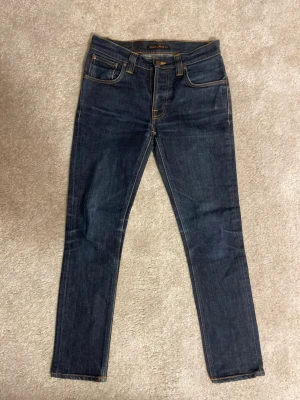 Nudie Jeans - Grim Tim - Säljer dessa riktigt snygga marinblåa Nudie Jeans Grim Tim i storlek 30 30! Jeansen har en riktigt sjysst wash och är i mycket bra skick! Nypris 1600 kr! Slim/straight fit!   Dessa jeans är i färgen ”Dry Navy” vilket betyder att ju mer du använder dem ju bättre blir mönstret/washen på jeansen!   Hör av er ifall ni har några frågor! ⚜️🙌⭐️