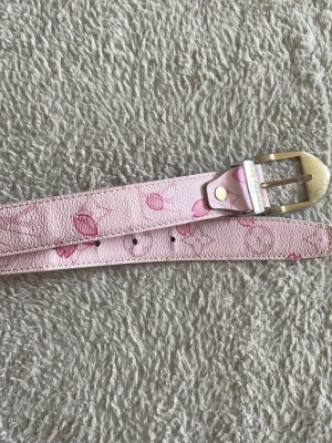 Rosa bälte - Perfekt för att lysa upp din stil. Den har rosa blomdetlajer osv. Den är köpt från secondhand.