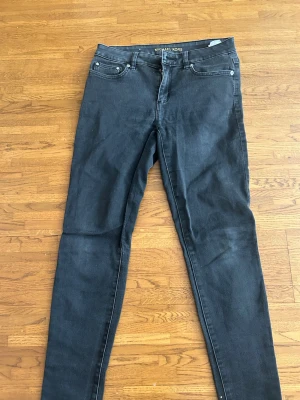 Svarta skinny jeans från Michael Kors - Säljer ett par svarta skinny jeans från Michael Kors med klassisk femficksdesign och dragkedja. Jeansen har en smal passform och är tillverkade i stretchigt denim som sitter snyggt och bekvämt. Perfekta för dig som gillar stilrena och trendiga jeans.