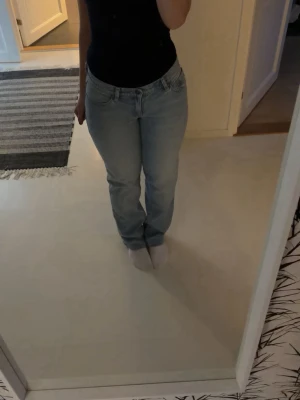 Ljusblå raka jeans - Säljer ett par ljusblå jeans med rak passform och klassisk femficksdesign. Jeansen har normal midja och stängs med dragkedja och knapp. Perfekta för en avslappnad och stilren look. Nypris på 1000