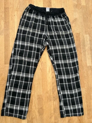 Rutiga pyjamasbyxor i svartvitt - Mysiga pyjamasbyxor med svart och vitt rutmönster. Byxorna har resår i midjan och raka ben, perfekta för chillkvällar hemma. Tillverkade i mjukt bomullstyg som känns skönt mot huden. 