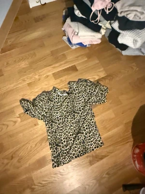 Leopardmönstrad t-shirt - Cool t-shirt med leopardmönster i beige, svart och brunt. T-shirten har korta ärmar och rund halsringning. Perfekt för dig som vill sticka ut med ett djurmönstrat plagg. Materialet känns mjukt och bekvämt mot huden.