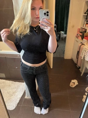 Svarta lågmidjade leopardmönstrade bootcut jeans - Säljer ett par svarta jeans med diskret leopardmönster. Jeansen är bootcut, låg midja och är gjorda av en tjej på plick. Materialet känns bekvämt, perfekta för dig som vill ha något lite extra i garderoben. Dessa har varit en favorit i garderoben!