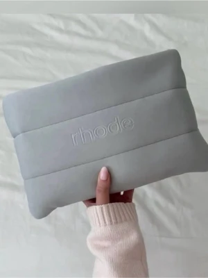 Rhode bubble bag in unsented grey colour - Snygg ljusgrå necessär från Rhode i mjukt, vadderat material med broderad logga framtill. Rektangulär form med dragkedja upptill och rymligt fack. Perfekt för smink eller småprylar. Enkel och stilren design som passar i väskan.