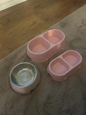 Rosa matskålar för husdjur - Tre matskålar för husdjur, två rosa dubbelskålar i plast och en rund skål i metall med rosa plastkant. Perfekt för både mat och vatten till katt eller liten hund. Snygg och enkel design som passar in i de flesta hem.