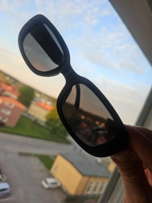 Svarta rektangulära solglasögon - Snygga svarta solglasögon med rektangulära bågar och mörka glas. Aldrig använda