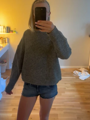 Grå stickad tröja - Mysig mörkgrå stickad tröja med avslappnad passform och rund hals. Tröjan har långa ärmar och ribbade muddar vid ärmslut och nederkant. Perfekt för kyliga dagar och enkel att matcha med olika outfits. Perfekt till senare sommarkvällar att bara slänga på sig. Har för många stickade tröjor och därför kommer den ej till användning tvättas innan jag skickar den💖