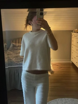 Vitt loungewear-set med kortärmad tröja - Mysigt vitt loungewear-set med kortärmad, lös stickad tröja och matchande byxor med struktur. Perfekt för chill dagar hemma. Materialet ser mjukt och bekvämt ut, och setet har en avslappnad passform.