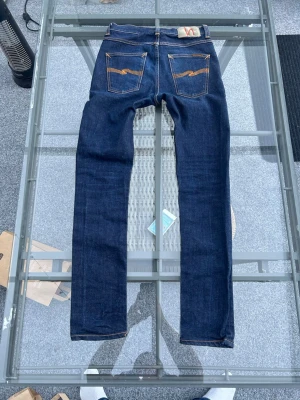 Nudie Jeans Lean Dean – Dry 16 Dips, W28 L32 - Säljer mina Nudie Jeans i modellen Lean Dean, en riktig klassiker med snygg passform. Den här tvätten, ”Dry 16 Dips”, är en mörk och tidlös denim som passar till allt.  Modell: Lean Dean (slim fit med avsmalnande ben).  Storlek: W28 L32.  Material: 99 % ekologisk bomull och 1 % elastan.  Skick: Mycket fint begagnat skick, väl omhändertagna. Perfekta jeans för dig som vill ha hållbar kvalitet och en modern silhuett. Skriv gärna om du har några frågor eller vill ha fler bilder! 