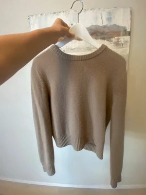 Beige kashmir tröja med rund hals - Mysig beige Kashmir tröja med rund halsringning och långa ärmar. Tröjan har ribbade muddar vid ärmslut och nederkant, vilket ger en snygg och avslappnad look. Perfekt att matcha med jeans eller kjol för en enkel och stilren outfit. Köptes för 1500kr🩷