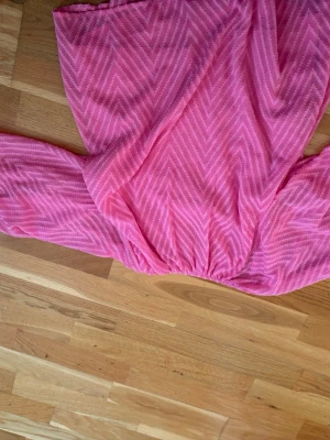 Rosa blus med mönster från Vero moda  - Säljer en rosa blus från vero  moda med vitt sicksackmönster. Blusen har vida, trekvartsärmar med resår vid ärmslut och en lös passform. Perfekt för dig som gillar färg och mönster!