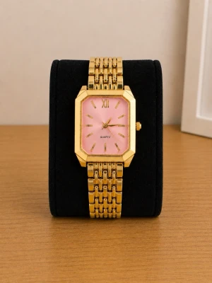 Guldig klocka med rosa urtavla - Stilren klocka med fyrkantigt guldigt armband och boett. Urtavlan är rosa med guldiga visare och index, vilket ger en trendig och elegant look. Perfekt accessoar för att lyfta din outfit med en touch av färg och lyx.
