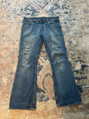 Levi's 529 bootcut jeans W32 L32 - Säljer ett par klassiska blå Levi's 529 bootcut jeans med slitningar och hål på vänster lår. Riktigt skön wash. Priset är inte hugget i sten