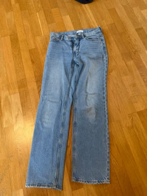 Ljusblå raka jeans  - Säljer ett par ljusblå jeans med rak passform och medellåg midja. Jeansen är från gina tricot och har  tyvärr blivit för små för mig. På bild 3 ser man att det är två små hål på insidan av midjan av anledningen att när jag köpte jeansen så var de för stora så jag gjorde små hål för skosnöre i midjan, hålen syns ej på utsidan av jeansen. 