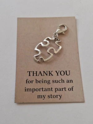 Silverfärgat pusselbit nyckelring - Unikt nyckelrings hänge i form av en pusselbit i silverfärgad metall. Hänget har en öppen design och en smidig karbinhake som gör det enkelt att fästa på ett armband eller kedja också. Personliga detaljer och symbolik med budskap och citat. Materialet rostfritt stål 