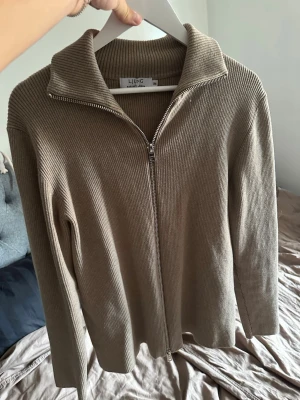 Beige ribbad ziptröja från Ljung - Snygg beige ribbstickad ziptröja från Ljung med hög krage och dragkedja hela vägen. Använt fåtal gånger. Nypris 1400