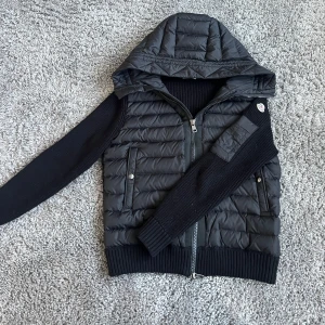 Moncler cardigan - Säljer en snygg svart cardigan från moncler. Jackan är i perfekt skick och perfekt nu för sommarkvällar. Har NFC Scan och även äktehets bevis från moncler då jag köpte den av en kompis.😃 jackan är i storleken 2 vilket är S/M