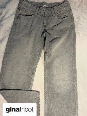 Grå jeans från Gina Tricot - Ett par snygga grå jeans från Gina Tricot med klassisk femficksdesign och raka ben. Jeansen har bälteshällor, knappstängning och är tillverkade i mjukt denim-material. 