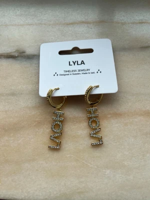 Hov1 örhängen - Örhängen från Lyla. Använda endast 2 ggr så iprincip nyskick! De är guldiga med ”diamanter” på. Tror att de kostade ungefär 300 nya
