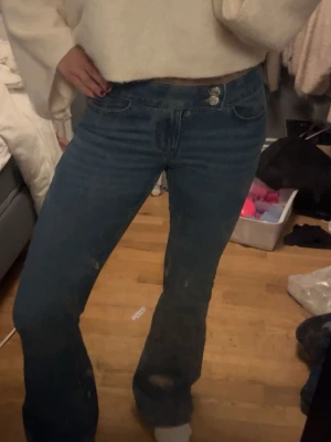 Blå bootcut jeans med lågmidja - Säljer ett par blå bootcut jeans med hög midja och klassisk femficksdesign. Jeansen har utsvängda ben och stängs med knapp och dragkedja. Använt cirka 1-2 gånger. 