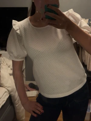 Vit blus med puffärmar och broderi - Snygg vit blus med puffiga kortärmar och broderade hål för en luftig känsla. Knappt använd 