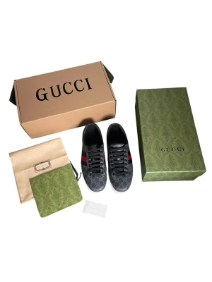 Gucci ace sneakers  - Snygga Gucci sneakers i svart och grå GG Supreme canvas med klassiska röda och blå ränder på sidorna. Lågt skaft, svarta skosnören och vit sula. Ikonisk design med diskret Gucci-mönster och exklusiva detaljer. Perfekta för dig som vill sticka ut med stil.