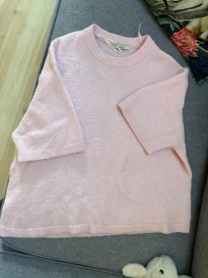 Ljusrosa stickad tröja Gina Tricot - Supermjuk ljusrosa stickad tröja från Gina Tricot med halvlånga ärmar och ribbade muddar vid hals, ärmslut och nederkant. Perfekt för lager-på-lager och enkel att styla till olika looks.