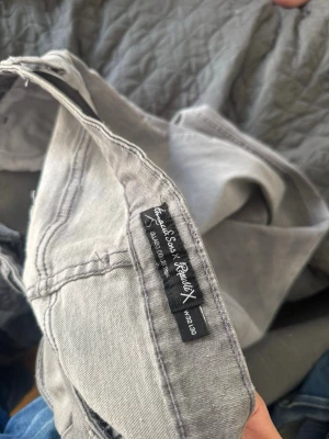 Gråa slim fit jeans med slitningar från (Amaci ’Sons) W32 L30 - Snygga grå jeans från Amaci Son med skinny fit och slitna detaljer på benen. Jeansen har klassisk femficksdesign och knappgylf. Perfekta för en trendig och avslappnad stil. W32 L30