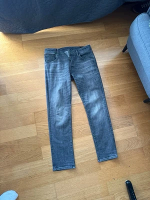 Grå slim fit jeans från Jack&Jones W33 L32 - Snygga grå slim fit jeans från Jack&Jones med klassisk femficksdesign och diskreta slitningar framtill. Jeansen har normal midja och smala ben, perfekta för en trendig och avslappnad look. Tillverkade i stretchigt denimtyg för extra komfort. W33 L32