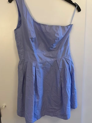 Ljusblå oneshoulder klänning - Snygg ljusblå klänning med oneshoulder-design. Kjolen har veck för volym och är perfekt för varma sommardagar! 🩵 Säljer den då den tyvärr är för liten för mig. Använd fåtal gånger och är i fint skick! 🪼Hör av dig vid några funderingar eller fler bilder! 🤭