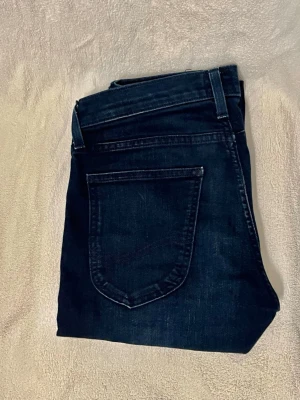 Lee jeans - Snygga mörkblå jeans från Lee med klassisk femficksdesign och raka ben. Jeansen har en diskret Lee-logga på bakfickan och är tillverkade i ett mjukt denimtyg som sitter skönt. Perfekta för dig som gillar en stilren look. Oanvända 