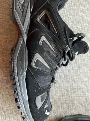 Svarta Treksta sneakers med grå detaljer - Säljer ett par svarta sneakers från Treksta med grå detaljer och robust sula. Modellen är Granit GTX w, Skorna har meshpaneler för extra ventilation och förstärkta partier i syntetmaterial. Byggda med Gore tex. Perfekta för dig som gillar en sportig och funktionell stil eller skall börja vandra. Använda en eftermiddag på gården.