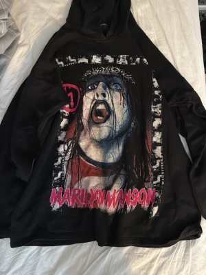 Marilyn Manson  hoodie - Säljer en svart hoodie med tryck från Marilyn Manson och albumet Antichrist Superstar. Hoodien har huva och är perfekt för dig som gillar alternativ stil. Finns ingen storlek men skulle säga att den är M/L. Funkar på mig som brukar ha S men då blir den lite stor.