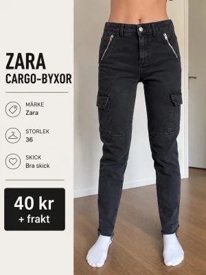 Svarta cargobyxor från Zara - Säljer ett par svarta cargobyxor från Zara med raka ben, dragkedjefickor framtill och klassiska cargofickor på sidorna. Byxorna har hög midja och är tillverkade i ett mjukt bomullsmaterial. Perfekta för en avslappnad och trendig look. 