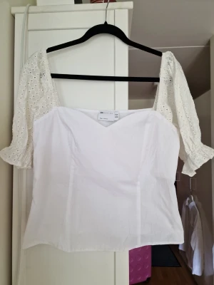 Vit blus med broderade puffärmar - Superfin vit blus från Asos med broderade puffärmar och v-ringad hals. Toppen har en feminin och romantisk look med korta ärmar i spets och lätt rynk vid ärmslut.Storlej 42 men mer som M eller L. Perfekt att styla med jeans eller kjol.