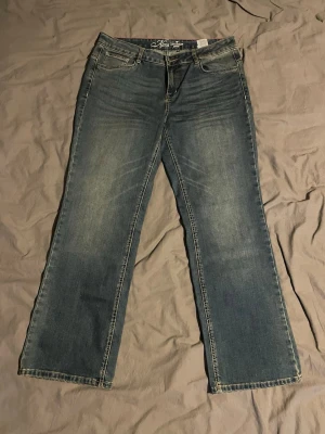 Blå bootcut jeans från Tom Tailor - Snygga blå bootcut jeans från Tom Tailor med klassisk femficksdesign och ljusa slitningar framtill. Jeansen har normal midja och bootcut ben, perfekta för en avslappnad och trendig look. Materialet är mjukt denim med lite stretch för extra komfort.