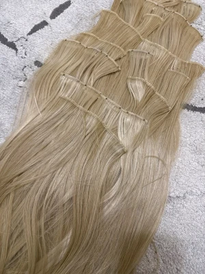 Blonda clip-on löshår extensions - Säljer blonda clip-on löshår extensions i flera delar för enkel applicering. Håret är långt, rakt och har en naturlig blond nyans. Perfekt för dig som vill ha extra volym och längd på ett smidigt sätt. Materialet är syntetiskt hår i 60 cm. 