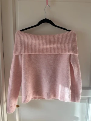 Ljusrosa off shoulder stickad tröja - Söt ljusrosa stickad tröja med bred off shoulder-krage och ribbstickade detaljer. 