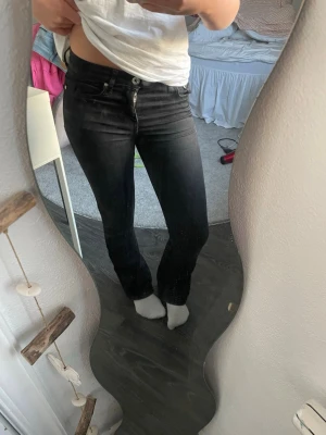 Svarta bootcut jeans med stretch lågmidjade - Säljer ett par svarta jeans med rak passform och stretchigt material. Jeansen har klassisk femficksdesign, normal midja och dragkedja med knapp framtill. Perfekta för dig som gillar en enkel och stilren look.
