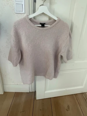 Ljusrosa stickad tröja  - Mysig ljusrosa stickad tröja från Lindex med rund halsringning och kortare ärmar. Tröjan har en enkel och avslappnad passform.