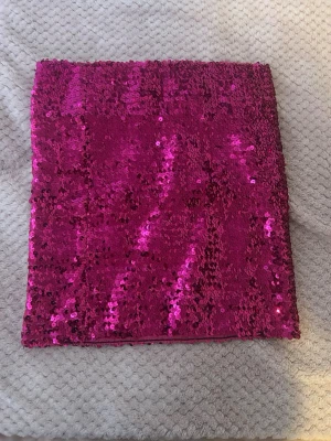 Rosa paljettkjol  - Säljer en glittrig rosa tub i stretchigt tyg täckt av paljetter. Perfekt för dig som vill sticka ut med en färgstark accessoar eller topp. Materialet är mjukt och följsamt med massor av glans och glittereffekt.